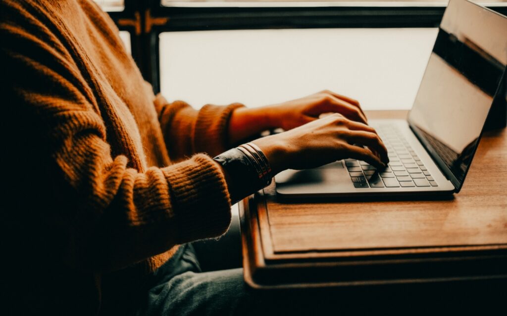 Eine Person arbeitet an einem Laptop am Schreibtisch.