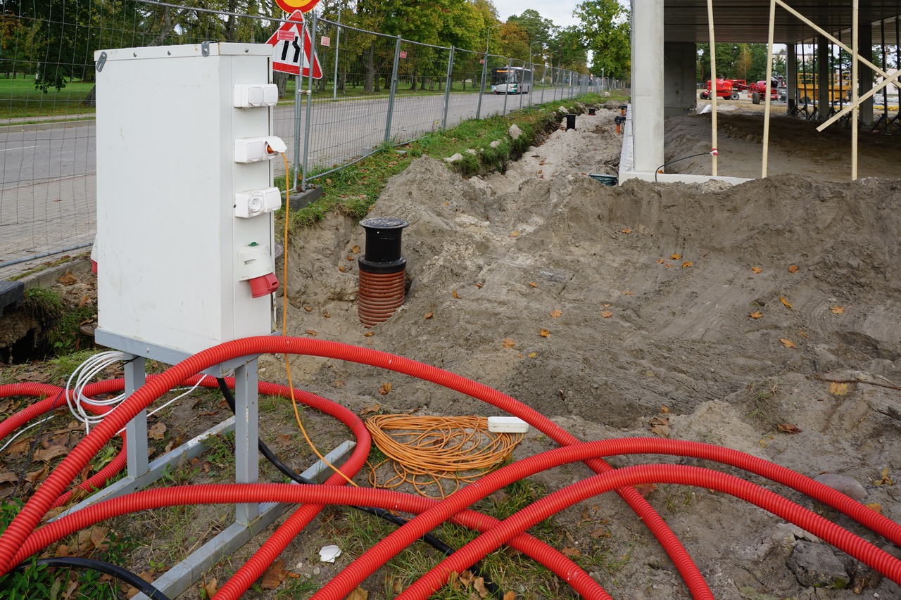 Baustromverteiler mit roten Kabelschutzrohren auf einer Baustelle