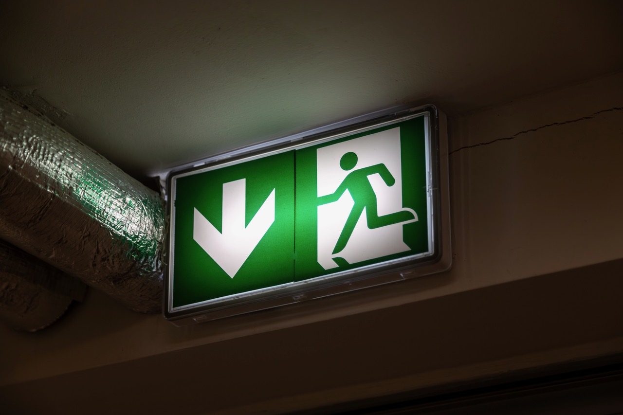 Beleuchtetes grünes Fluchtwegschild mit Rettungszeichen an der Decke